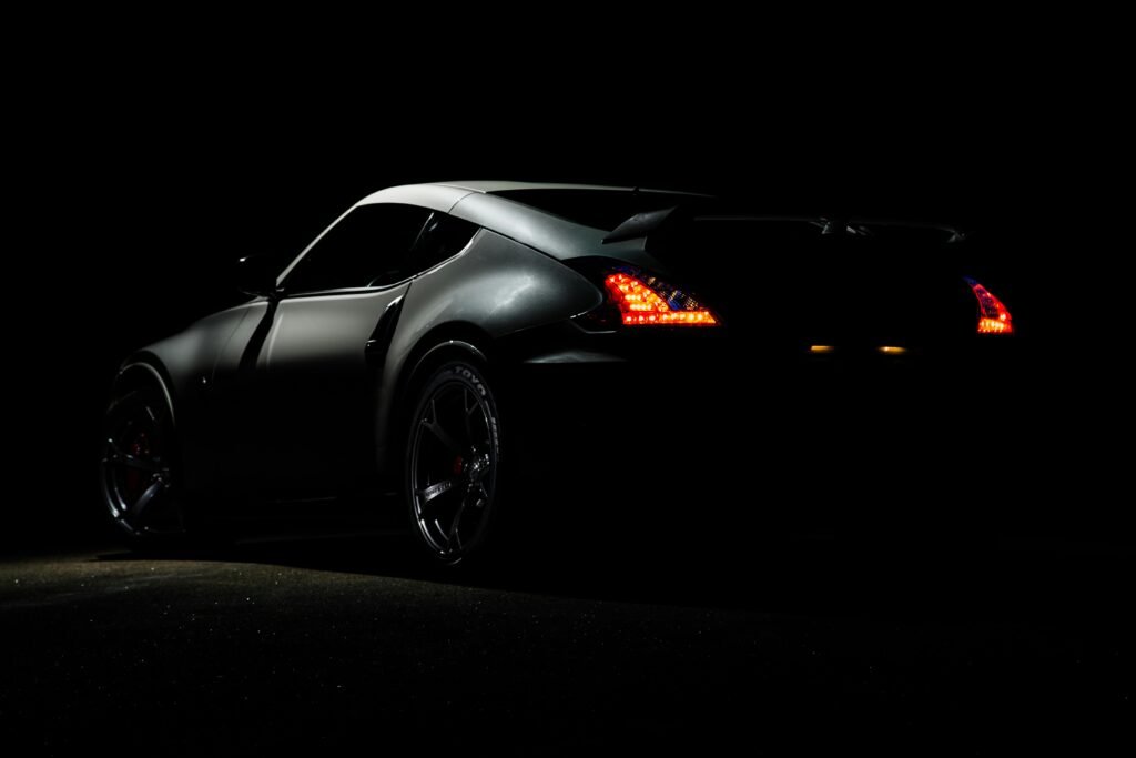 A dramatic shot of a Nissan 370Z sports car illuminated in darkness with vibrant tail lights.